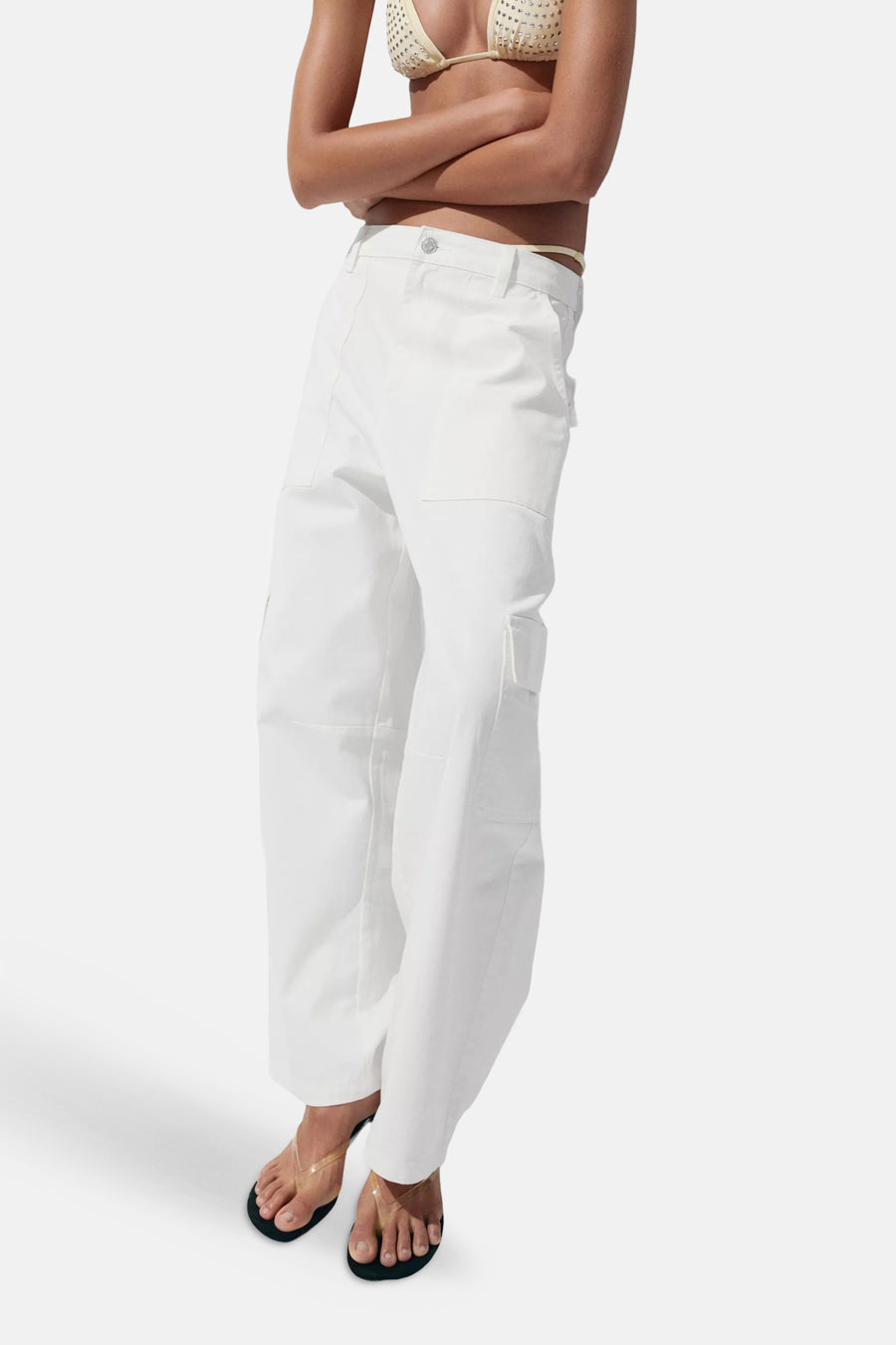 Witte rechte jeans van denim met zakken van MANGO, gedragen met een beige bikinitop en sandalen, zijprofiel.