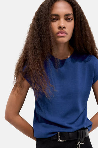 Blauwe mouwloze debardeur van MANGO, strakke pasvorm, ronde hals, gedragen met zwarte riem en krullend haar, front view