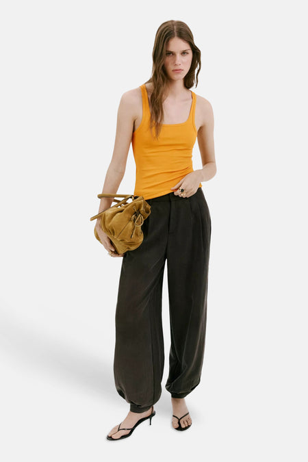 Oranje tanktop van MANGO, strak model met ruches, gedragen met zwarte wijde broek en bruine leren tas, lifestyle shot