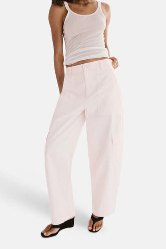 Roze cargobroek van MANGO, lichte stof, grote zakken, model in lifestyle pose, witte tanktop en zwarte sandalen