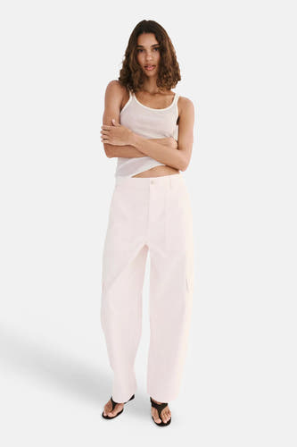 Roze cargobroek van MANGO, lichte stof, wijde pasvorm, voorzijde met zakken, model in full length pose met wit topje en sandalen