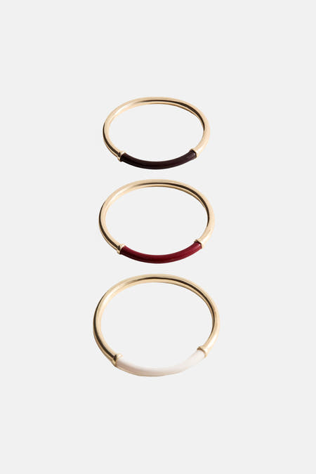 Multicolor armband van goudkleurig metaal met inzet van donkerrood, rood en wit, van MANGO, gestapeld in verticale rij op lichte achtergrond