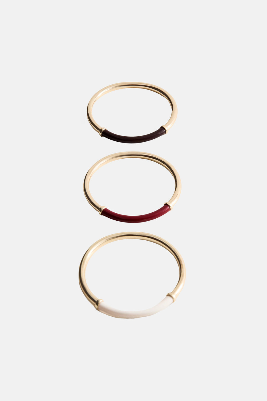 Multicolor armband van goudkleurig metaal met inzet van donkerrood, rood en wit, van MANGO, gestapeld in verticale rij op lichte achtergrond