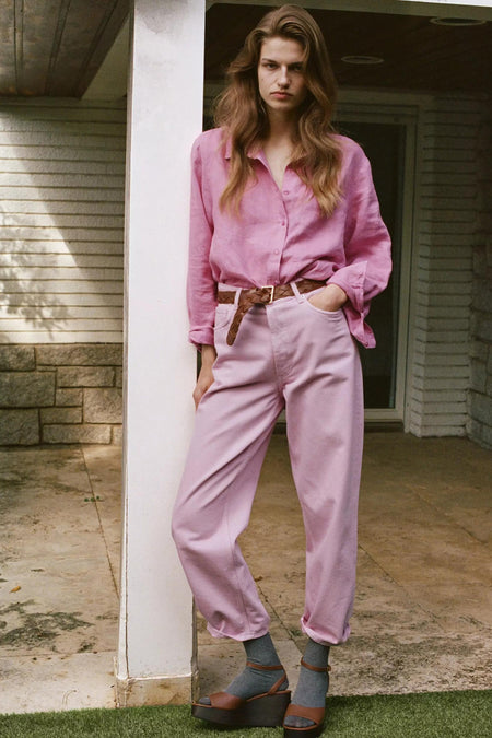 Roze lange mouwen overhemd van MANGO, licht gekreukt, met geknoopte mouwen, gedragen met roze broek en bruine gevlochten riem, lifestyle shot.