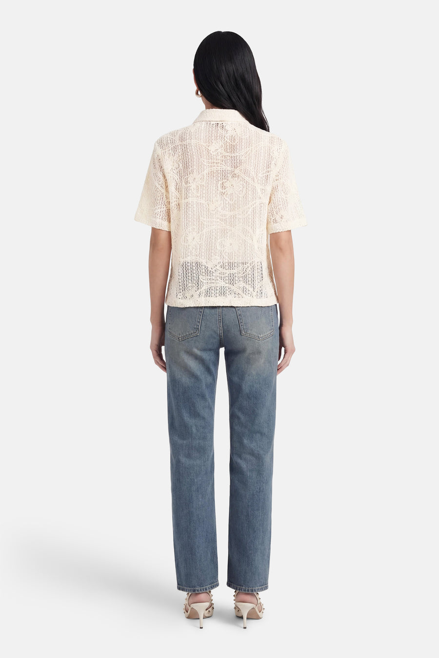 Chemisier beige à manches courtes de Terra di Siena, ajouré à motif floral, vue arrière, porté sur un jean et des talons.
