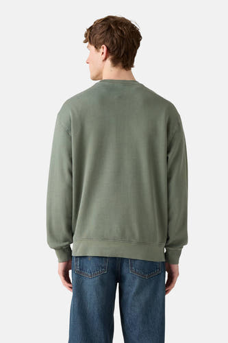 Sweater vert de Levi's® avec des manches longues et un col rond, associé à des jeans bleus.
