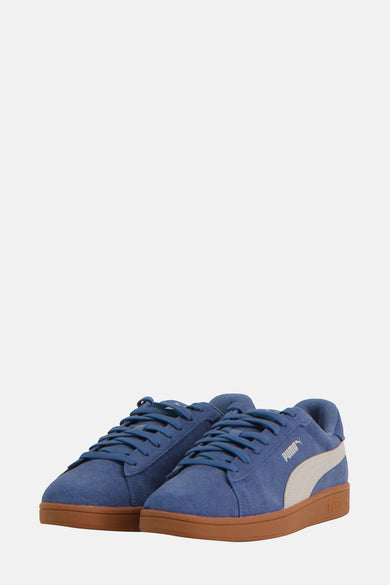 Sneakers bleues de PUMA, avec une semelle brune et une bande blanche sur le côté.