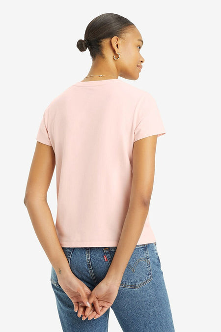 Vrouw met roze T-shirt en blauwe spijkerbroek, staand van achteren.