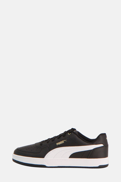 Sneakers noirs de PUMA, avec une bande blanche sur le côté et un bord de semelle noir.