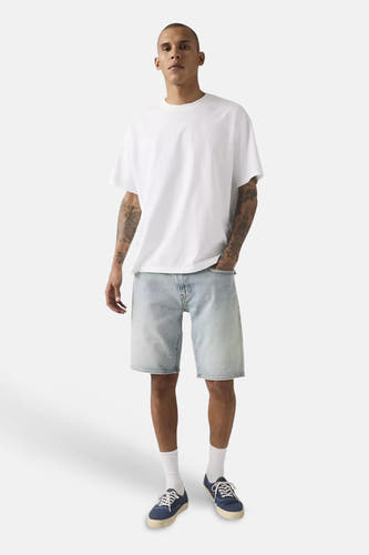 Lichtblauwe denim shorts van Levi's® met gewassen look, gedragen met wit T-shirt en blauwe sneakers, front view.