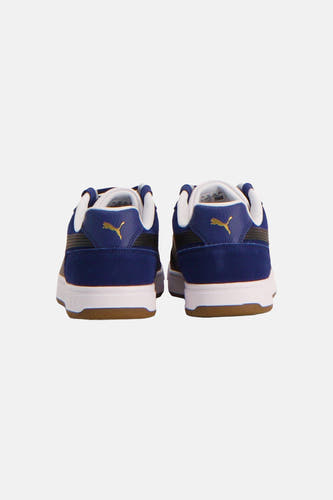 Baskets bleues PUMA avec semelles blanches et un logo doré sur le talon.