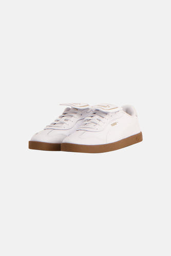Sneakers blanches de PUMA avec un logo doré sur la langue et une semelle brune.
