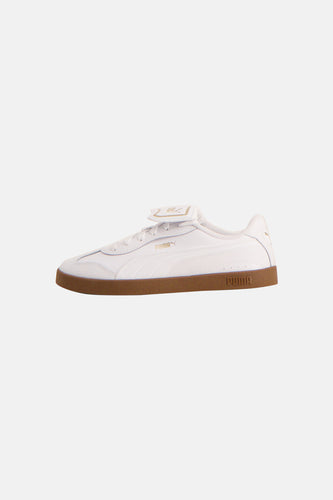 Sneakers blanches de PUMA avec une semelle brune et le logo PUMA en or.