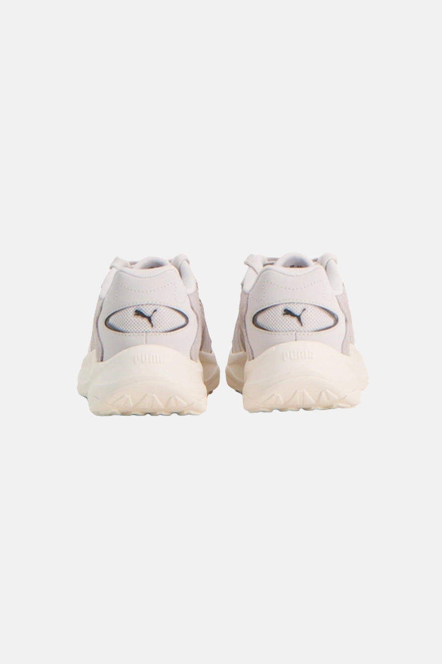 Achteraanzicht van een paar grijze sneakers van PUMA, met crèmekleurige zolen en het logo op de hiel.