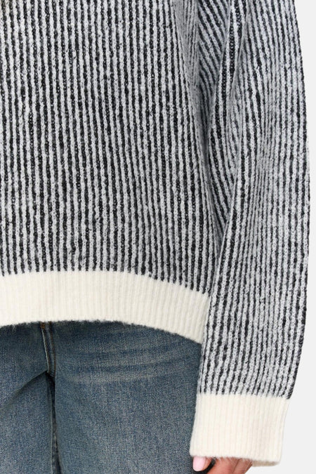 Trui met zwarte strepen en jeans.