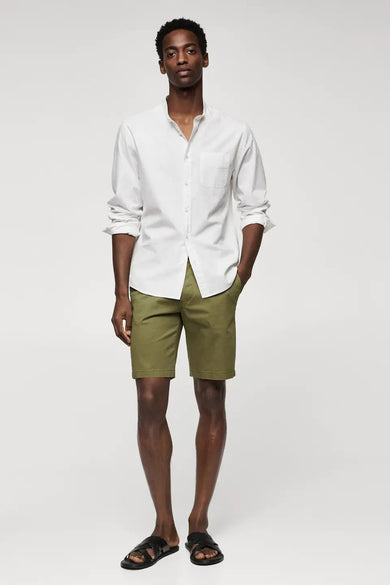 Short beige de MANGO, porté avec un chemisier blanc et des sandales noires.