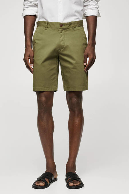Short beige de MANGO, porté avec un chemisier blanc et des sandales noires.