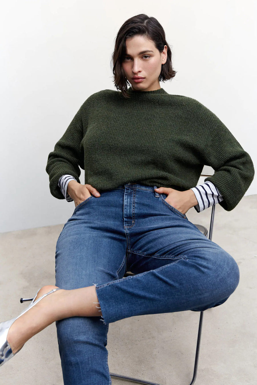Jean skinny bleu moyen en denim de MANGO avec un ourlet effiloché, porté par un mannequin assis.