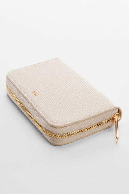 Portefeuille blanc à texture côtelée de MANGO, fermeture éclair dorée et design minimaliste, placé latéralement sur fond blanc