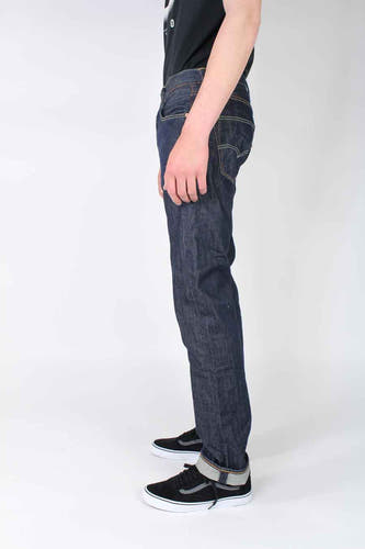 Jean droit bleu foncé de Levi's®, avec ourlets retroussés et porté avec des chaussures noires.