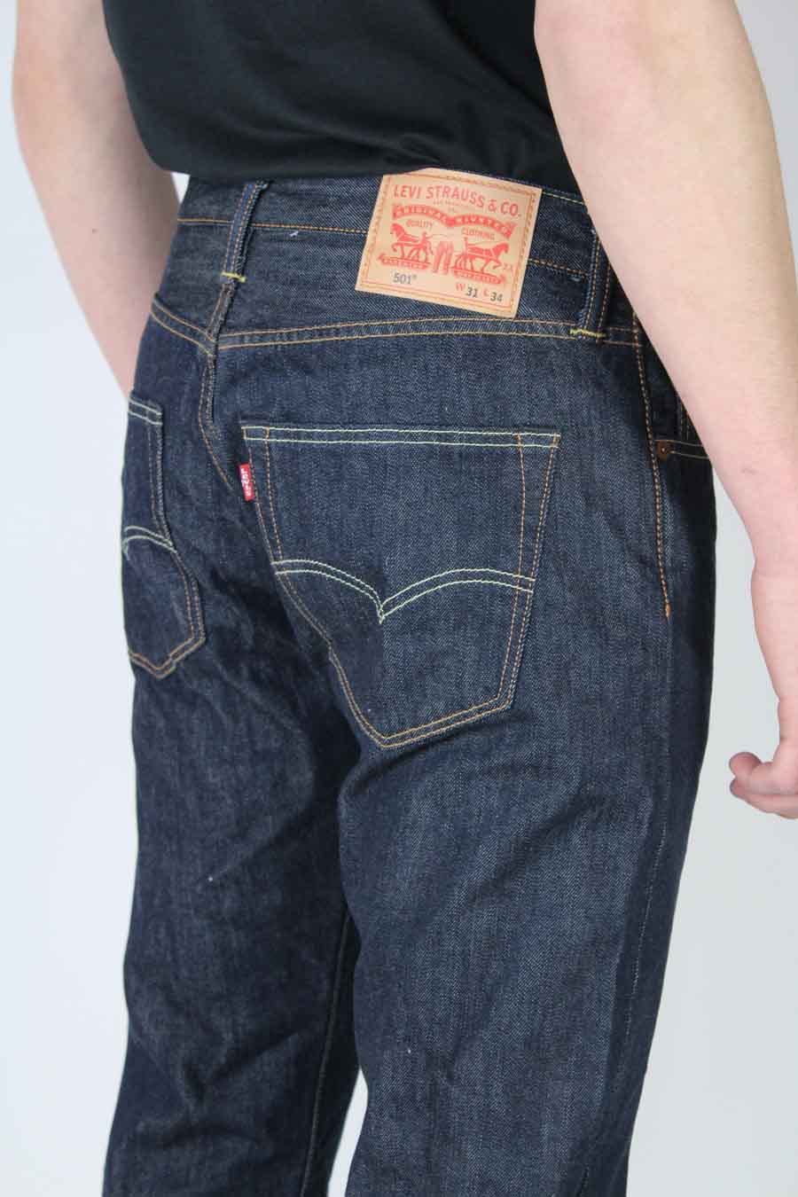 Jean droit bleu foncé de Levi's, avec étiquette rouge visible sur la poche arrière et patch en cuir sur la ceinture.