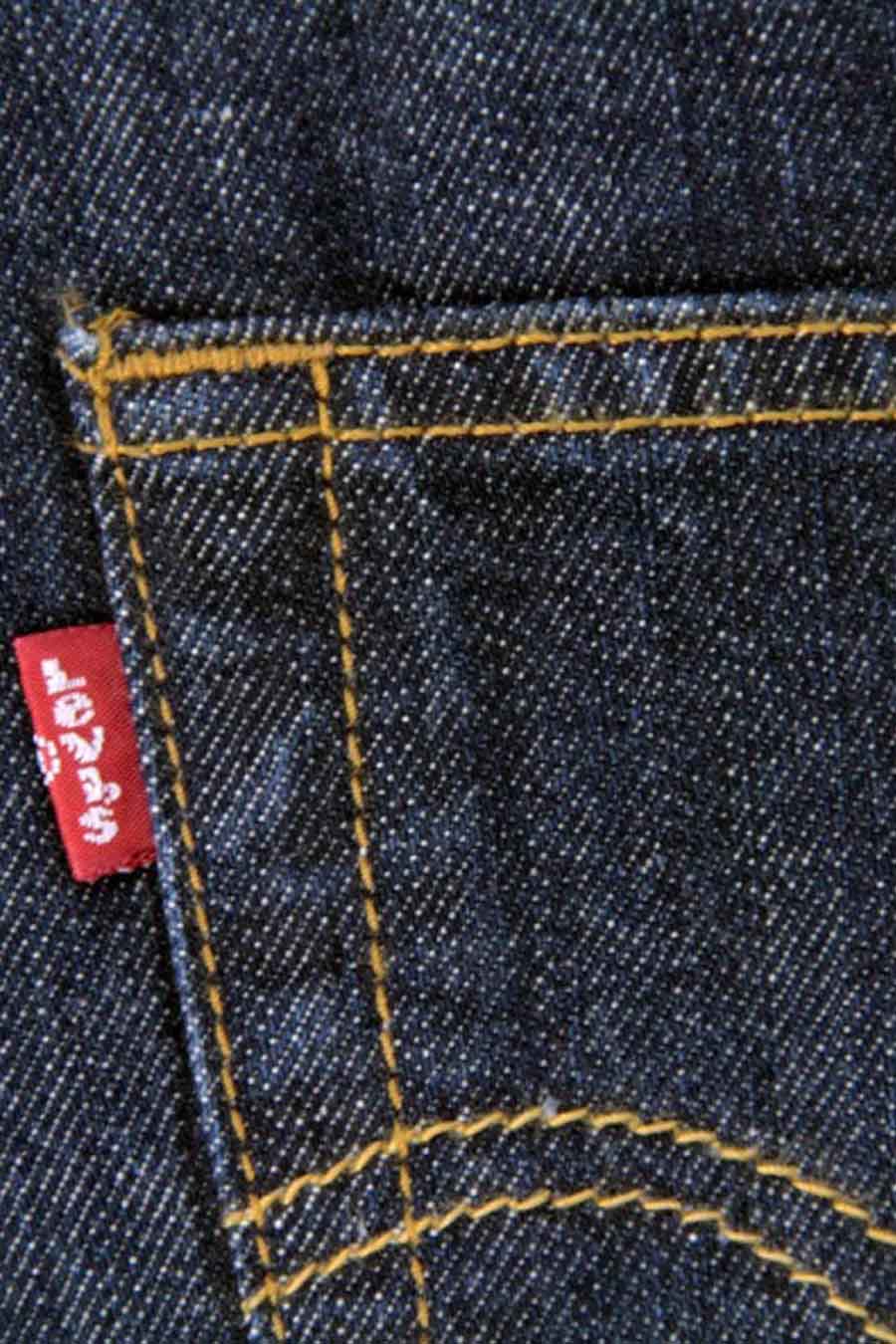 Jean droit bleu foncé de Levi's, avec surpiqûres jaunes et une étiquette rouge de la marque sur la poche arrière.