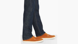 Jean droit bleu foncé de Levi's®, porté avec des mocassins marron à semelle et coutures blanches, en vue de côté.