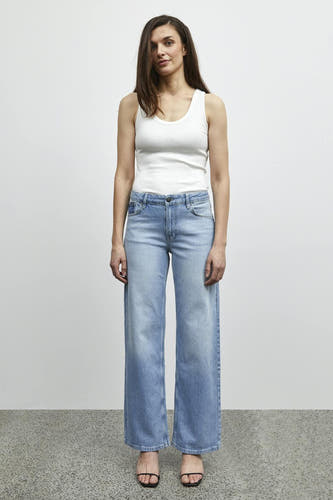 Jean bleu clair large de PULZ, associé à un tank-top blanc et des sandales noires.