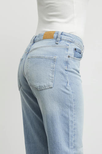 Jean en denim bleu clair large de PULZ Jeans, avec poche arrière et étiquette en cuir sur la ceinture.