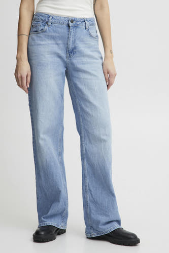 Jean bleu clair large de Pulz, associé à des chaussures noires, et avec un tatouage sur le bras.