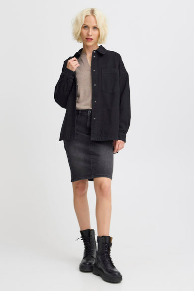 T-shirt en jean noir de PULZ, porté avec un pull beige, une jupe grise foncée et des bottes noires.