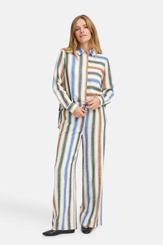 Pantalon multicolore de PULZ avec des rayures verticales et des jambes larges, porté avec une chemise à rayures coordonnée.
