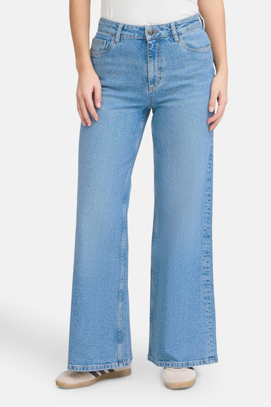 Jean large de denim bleu de PULZ, avec une taille haute et des poches fendues.