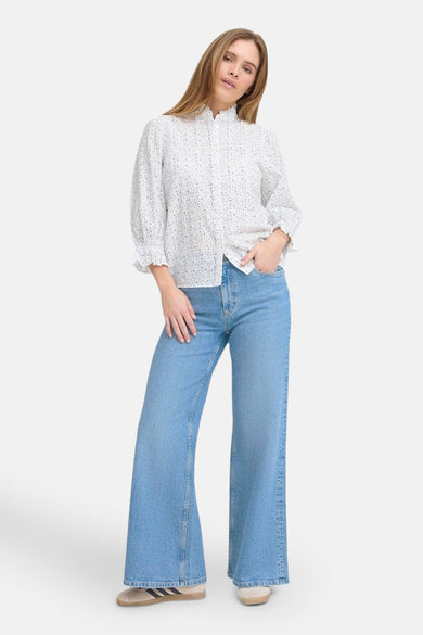 Jean décontracté en denim bleu moyen de PULZ, porté avec une blouse imprimée et des baskets basses.