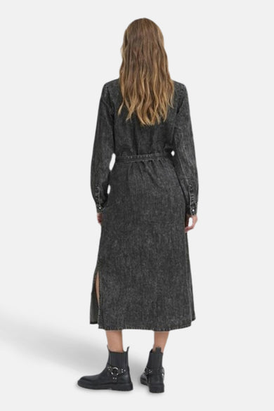 Manteau de denim bleu marine à longues manches de PULZ, avec ceinture et échancré à l'arrière, associé à des bottines noires.