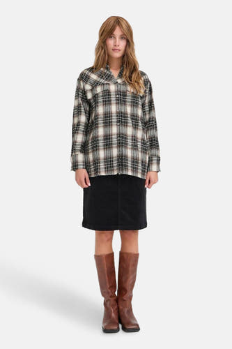 Chemise brune de PULZ, avec des manches longues et un motif à carreaux, portée avec une jupe noire et des bottes brunes.