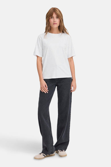 Wit T-shirt van PULZ, met subtiele versiering, gecombineerd met wijde, donkere jeans en sneakers.

