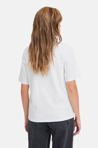 Wit T-shirt van PULZ, achterkant zichtbaar, gecombineerd met een grijze jeans.
