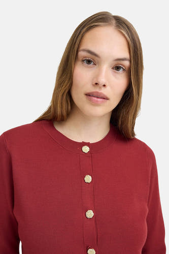 Gilet rouge de PULZ, avec des boutons dorés.