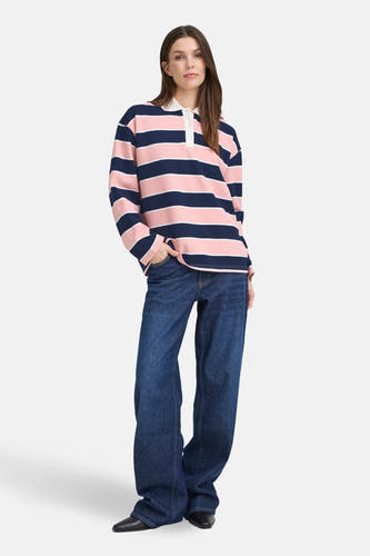 Pull multicolore de PULZ, avec des rayures horizontales roses et bleu marine, porté avec des jeans larges et des chaussures noires.