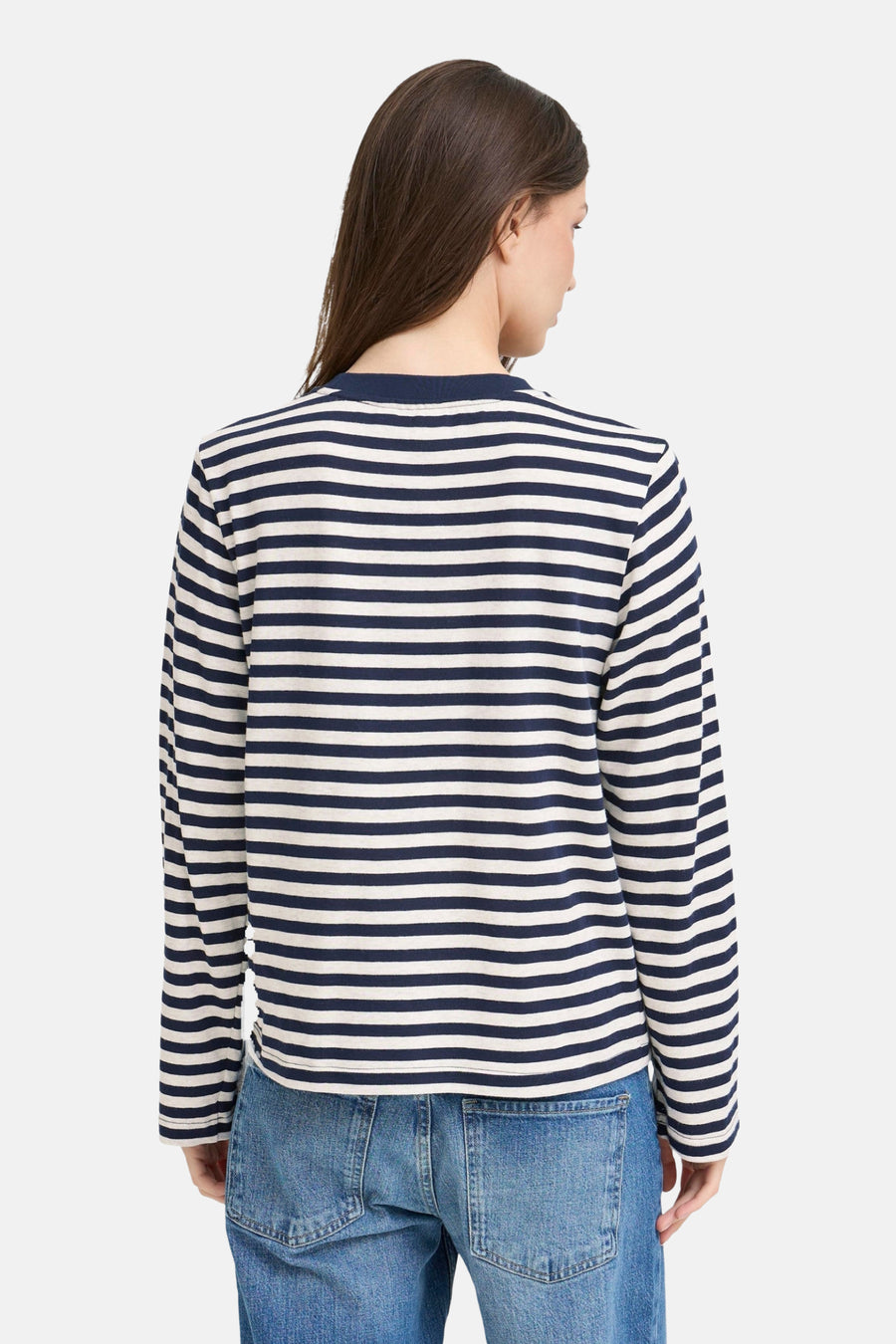 Achterkant van een vrouw in een gestreepte longsleeve en jeans.