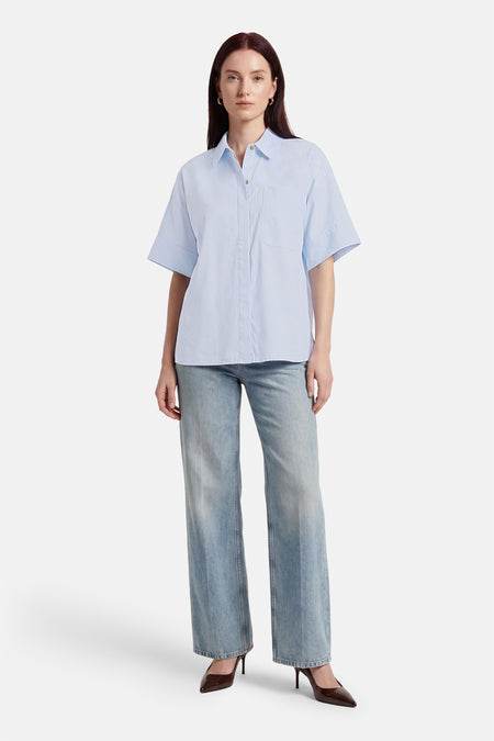 Blauw overhemd met korte mouwen van PULZ, met een borstzak, gedragen met jeans en hakken.