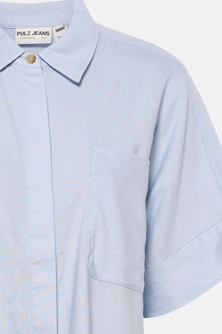 Chemise bleue à manches courtes de PULZ Jeans, avec une poche poitrine et une fermeture boutonnée.