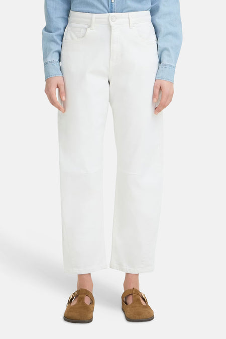 Jeans large blanc en denim de PULZ avec jambes raccourcies et poches arrière, portées avec une chemise en denim bleu clair et des mules marron.