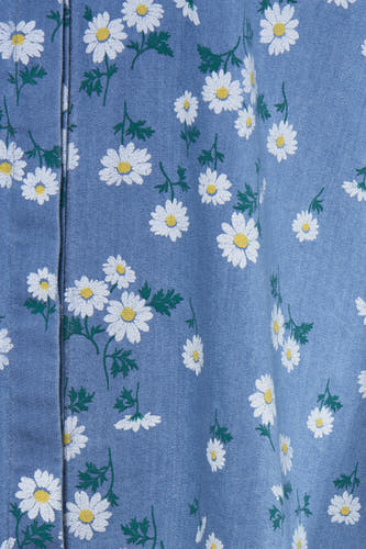 Chemise bleue à longues manches de Terra di Siena, avec un motif de marguerites blanches et de feuilles vertes.