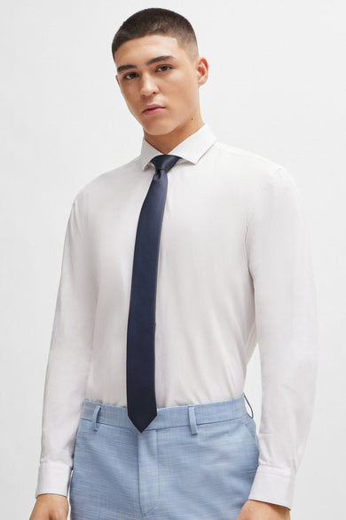 Jonge man, wit overhemd, blauwe broek, donkerblauwe stropdas.