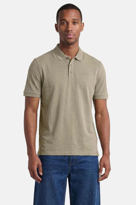 Polo verte HUGO verte de couleur verte avec deux boutons, un logo brodé, portée par un homme en jean.