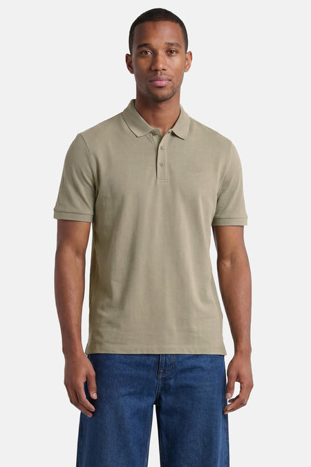Polo verte HUGO verte de couleur verte avec deux boutons, un logo brodé, portée par un homme en jean.