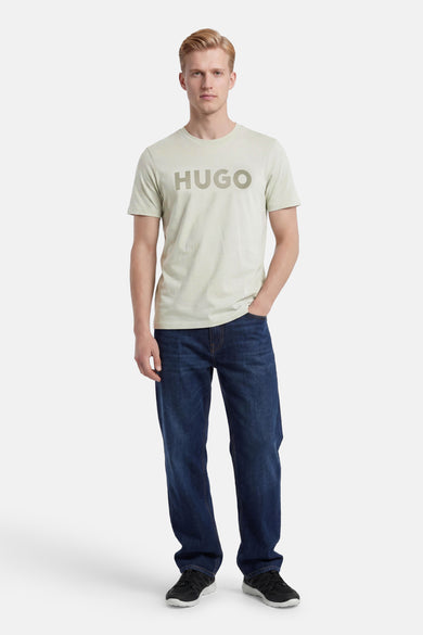 T-shirt vert de HUGO avec logo sur la poitrine, porté par un homme avec un jean foncé et des baskets.