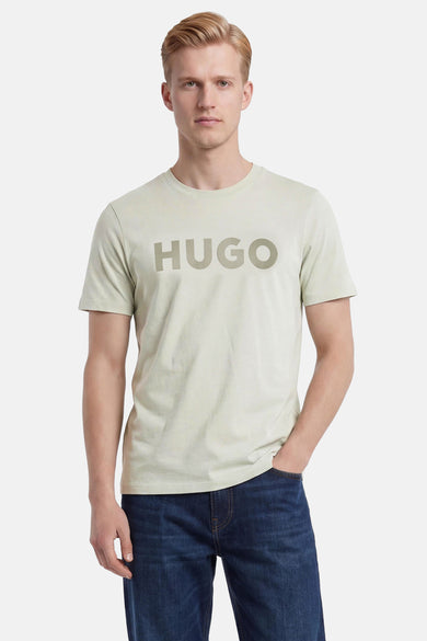 T-shirt vert clair de HUGO avec grand logo sur la poitrine, porté par un homme en jean bleu foncé.